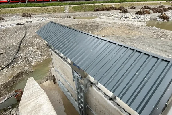 Einhausung der Rechenreinigungsanlage im Kraftwerk Stegenwald, im Hintergrund die Bahnstrecke