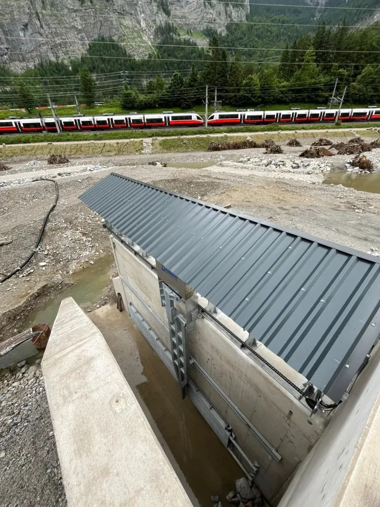 Einhausung der Rechenreinigungsanlage im Kraftwerk Stegenwald, im Hintergrund die Bahnstrecke